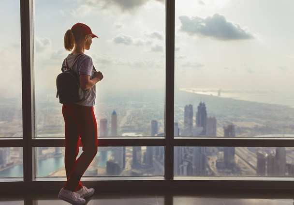 girl tourist at window of skyscraper of the Burj Khalifa in Duba - Photo, Image