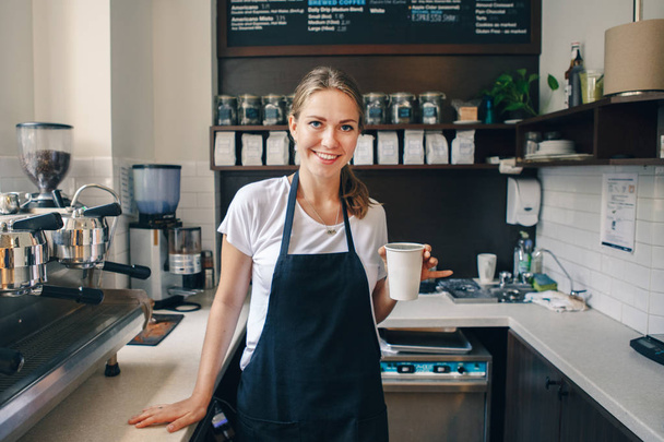 Νέοι Καυκάσιος barista χέρια που κρατούν το χαρτί Κύπελλο με τον καφέ. Μικρές επιχειρήσεις και πρόσωπο η ΕΝΝΟΙΑ ΤΗΣ ΕΡΓΑΣΙΑΣ - Φωτογραφία, εικόνα