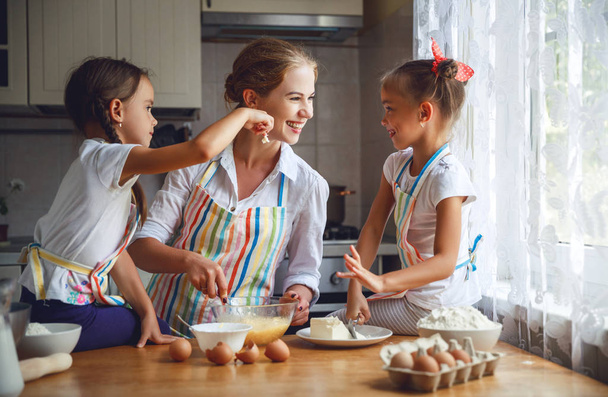 Happy family mother and children twins   bake kneading dough in  - Фото, изображение
