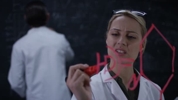 4K Scientists solving formulas, writing on glass screen and chalkboard - Video