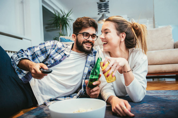 Ζευγάρι στην αγάπη, απολαμβάνοντας πίνοντας μπύρα και να παρακολουθούν τηλεόραση. - Φωτογραφία, εικόνα