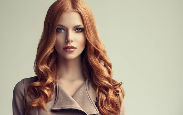 κόκκινα μαλλιά κορίτσι με σγουρά μαλλιά μακριά και λαμπερά. Το όμορφο μοντέλο γυναίκα με σγουρά hairstyle. Φροντίδα και την ομορφιά των μαλλιών - Φωτογραφία, εικόνα