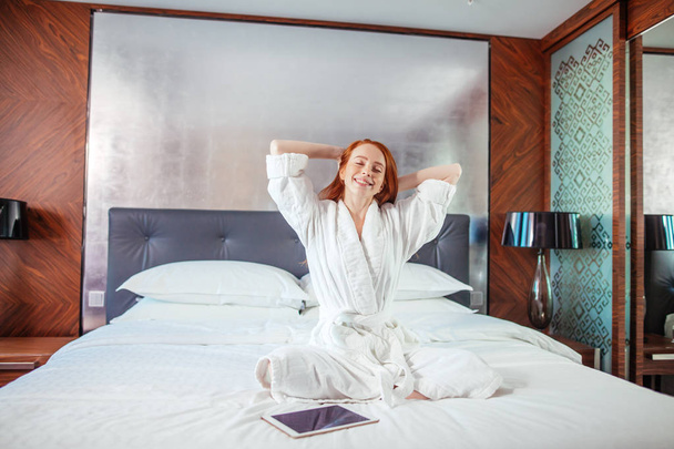 Punapää nainen venyttely sängyssä heräämisen jälkeen
 - Valokuva, kuva