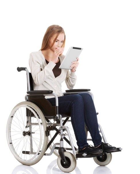 Beautiful casual woman sitting on w wheelchair with tablet. - Photo, Image