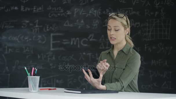 4K Mujer usando tableta en el aula, pizarra con fórmulas matemáticas en segundo plano
 - Metraje, vídeo