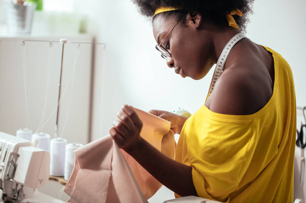 costurera mujer africana mirando telas rosadas y de pie en el taller - Foto, imagen