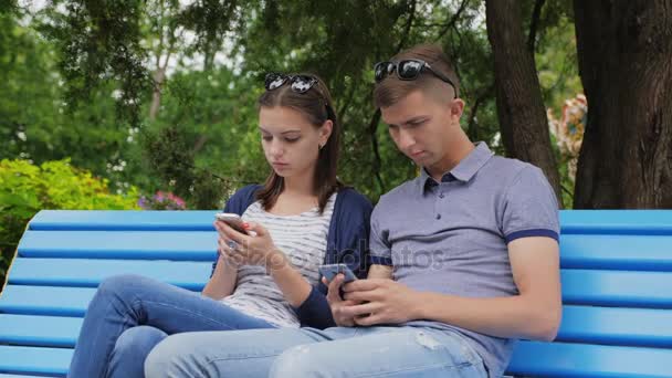 Ζευγάρι τη στιγμή αδιαφορία με τα τηλέφωνα σε εξωτερικούς χώρους, στο πάρκο της πόλης - Πλάνα, βίντεο