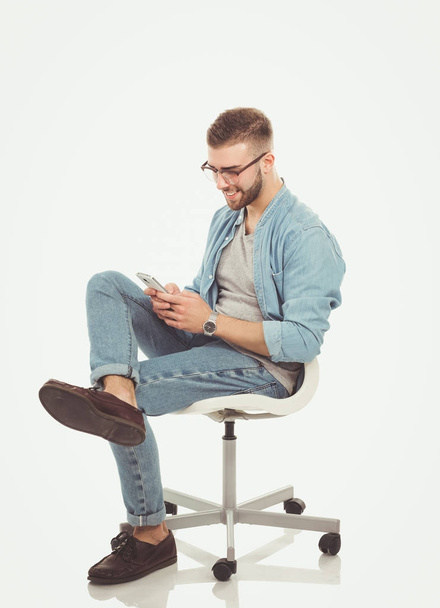 Young man sitting on chair and using mobile phone. Startupper. Young entrepreneur. - Фото, зображення
