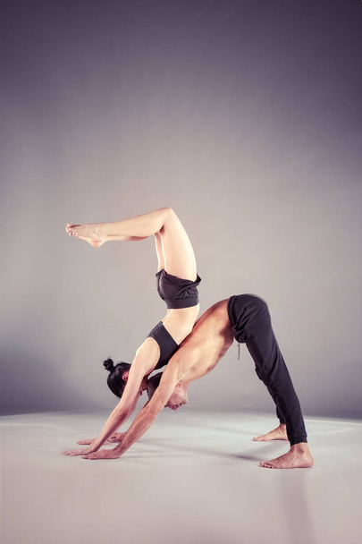 Young couple practicing acro yoga on mat in studio together. Acroyoga. Couple yoga. Partner yoga. - Zdjęcie, obraz