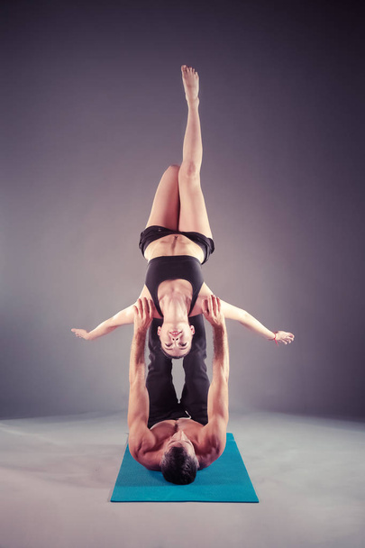 Young couple practicing acro yoga on mat in studio together. Acroyoga. Couple yoga. Partner yoga. - Foto, immagini