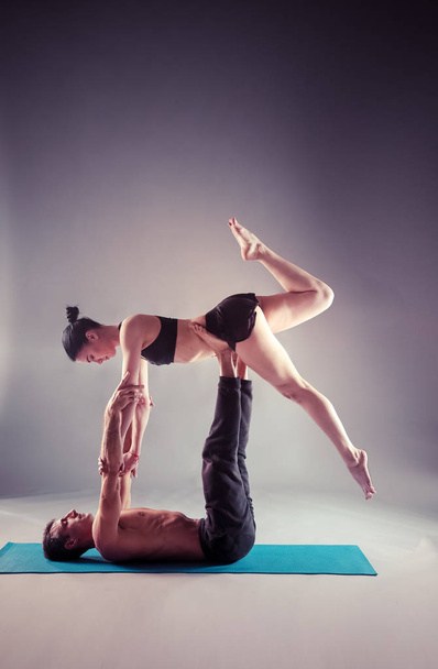 Young couple practicing acro yoga on mat in studio together. Acroyoga. Couple yoga. Partner yoga. - Foto, imagen