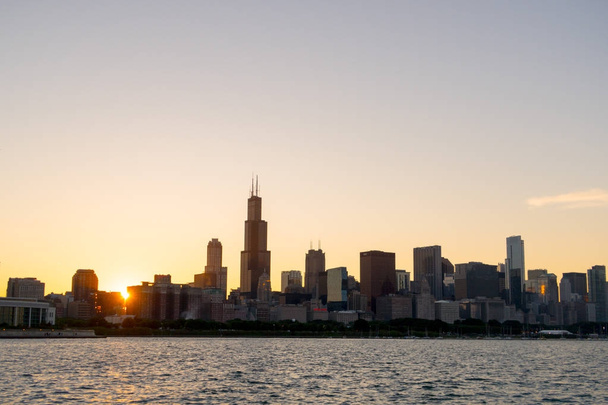 Chicago skyline picture during beautiful sunset with building silhouettes and rippling waves of Lake Michigan water in the foreground - Photo, Image