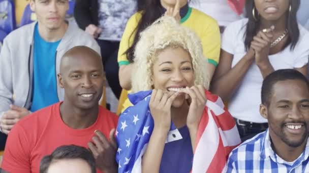Толпа 4K аплодирует своей команде на спортивном мероприятии, молодая женщина с флагом США
 - Кадры, видео