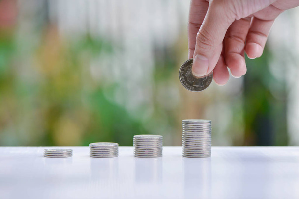 Žena ruku položil mince na rostoucí hromádky mincí - koncepce šetří peníze - Fotografie, Obrázek