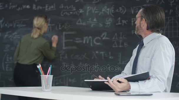 4K Portrait smiling academic man and woman studying math formulas on blackboard - Video