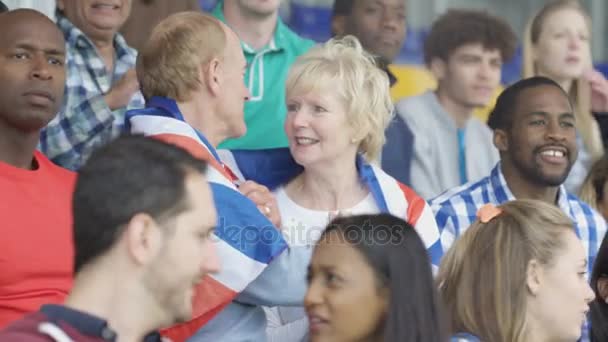 4k liebevolles reifes Paar in Menschenmenge bei Sportveranstaltung in britischer Flagge drapiert - Filmmaterial, Video