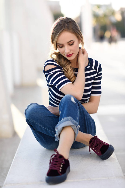 blonde Frau, Modell der Mode, sitzt im urbanen Hintergrund. - Foto, Bild