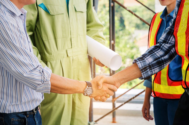 engineer and technician contractor shaking hands after finishing up a business meeting to greeting start up project contract in construction site building, successful, partnership, teamwork concept - 写真・画像