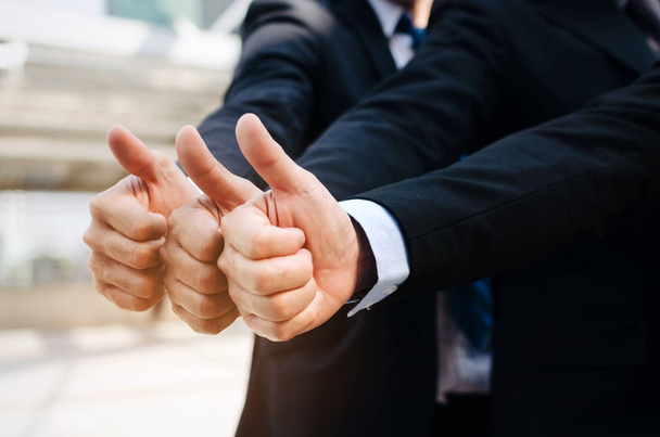 close up of hand group of handsome business people team in suit showing thumbs up as like sign together in the city, successful, support, meeting, partner, teamwork, community and connection concept - Foto, Bild