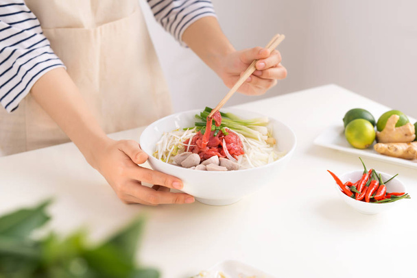 Θηλυκό σεφ προετοιμάζει παραδοσιακό βιετναμέζικο σούπα Pho bo με βότανα, κρέατα, noodles ρυζιού - Φωτογραφία, εικόνα