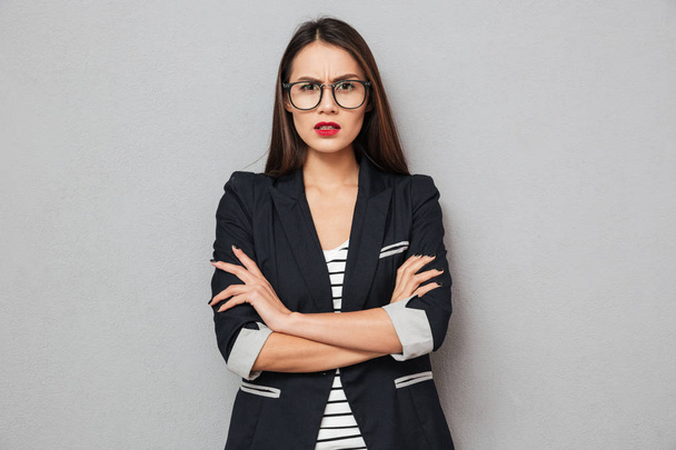 Serious asian business woman in eyeglasses with crossed arms - Fotó, kép