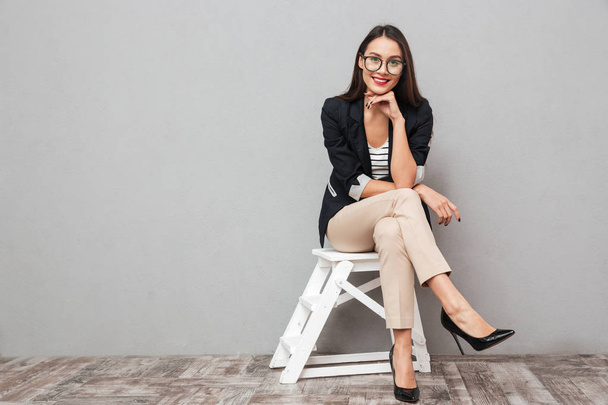 Smiling asian business woman in eyeglasses sitting on chair - Zdjęcie, obraz