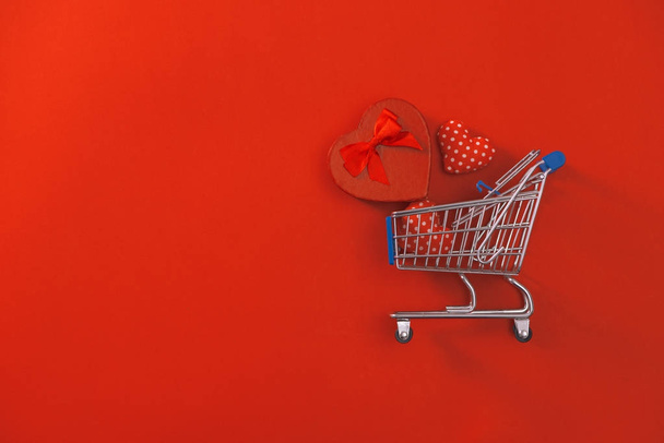 Winkelwagentje met luxe-geschenketui op rode achtergrond. Aftelkalender voor Valentijnsdag winkelen en verkoop. - Foto, afbeelding