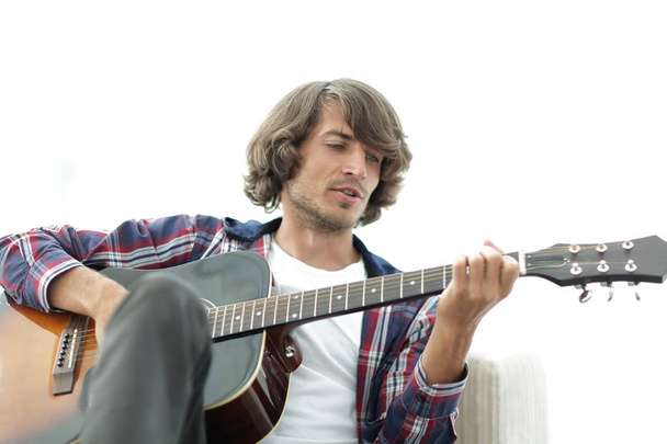 Hombre guapo tocando la guitarra en el sofá en casa
 - Foto, imagen