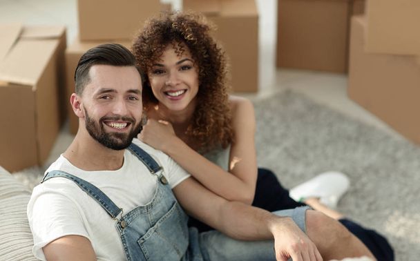 Young couple sitting on the floor in a new apartment - Foto, Imagen