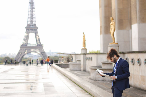 Mulatto pressman reading newspaper article near Eiffel Tower. - Foto, Imagem