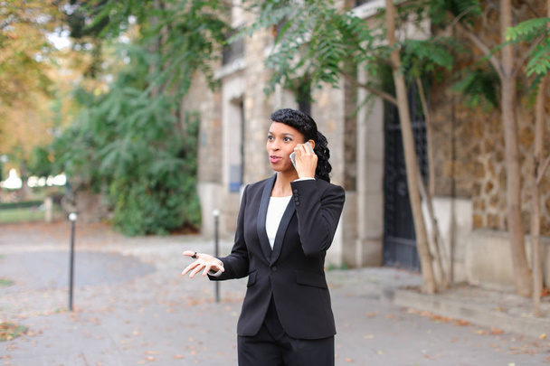 Schwarze Frau chattet draußen auf Smartphone. - Foto, Bild