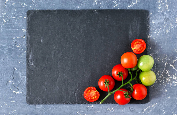Bunch of tomatoes on a black stone background - Zdjęcie, obraz