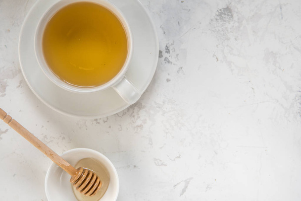 Tea and honey stick top view on a white background, copy space - Fotó, kép