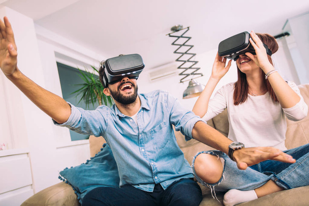 Νεαρός άνδρας και γυναίκα στο casual ρούχα φορούν τα γυαλιά εικονικής πραγματικότητας βλέποντας και δείχνοντας φανταστείτε μέσω της έννοιας Vr φωτογραφικών μηχανών, τεχνολογίας και καινοτομίας - Φωτογραφία, εικόνα