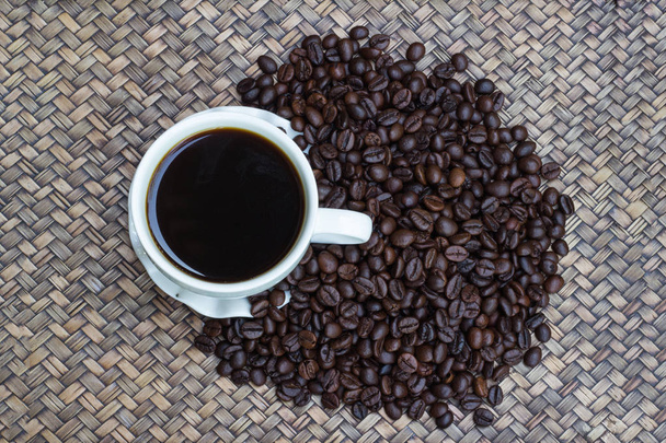 白いコーヒーのマグカップでコーヒー豆は、背景をぼかし、ホット コーヒーのカップは、コーヒー豆の横に配置さ - 写真・画像
