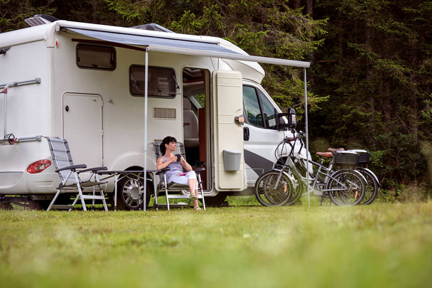 Woman is standing with a mug of coffee near the camper RV. - Fotó, kép