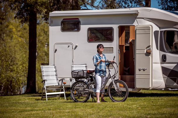 Woman on electric bike resting at the campsite VR Caravan car Va - Photo, image