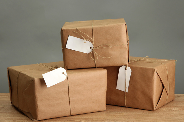 parcels boxes with kraft paper, on wooden table on grey background - Photo, image