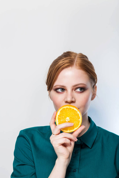 Portrait of beautiful woman with orange in her hand, looking with a smile to the side. Copy space. Health, nutrition, beauty, skin care. - Zdjęcie, obraz