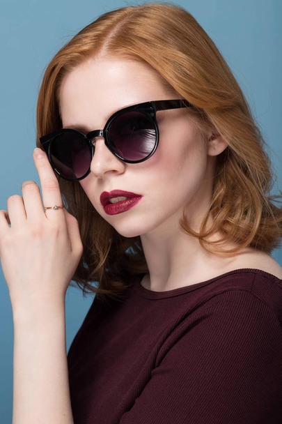 Close up portrait of stylish young woman in sunglasses against blue background. Fashion, glamour, fashion, model - Foto, Imagem