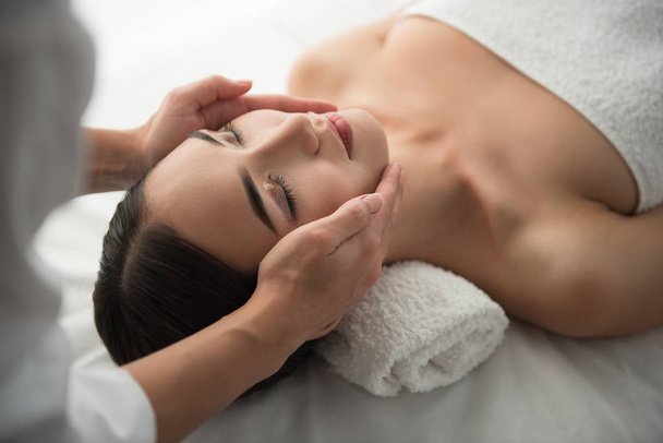 Brazos esteticistas haciendo masaje facial en el spa
 - Foto, Imagen