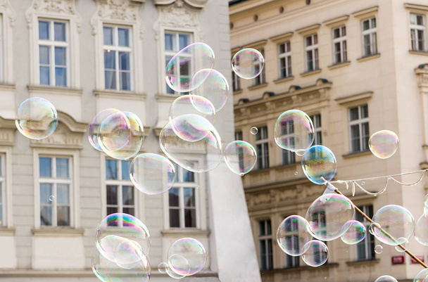 Large bright shiny soap bubbles fly against the background of a beige white house - Valokuva, kuva