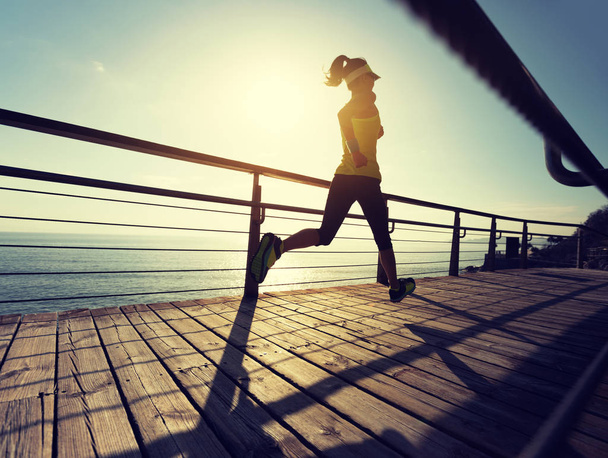 Sportos fitness női futó futó futó tengerparti sétányon napkeltekor - Fotó, kép