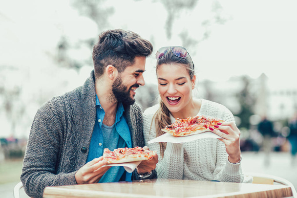 Пара їсть піцу на відкритому повітрі. Вони діляться піцою та їдять
. - Фото, зображення