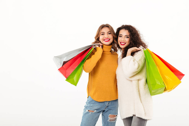 Two happy girls in sweaters with packages looking at camera - Φωτογραφία, εικόνα