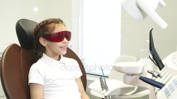 Onnellinen tyttö hammaslääkärin vastaanotossa näyttää peukalot ylös
 - Materiaali, video