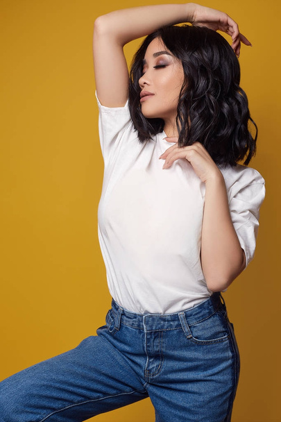 Elegant sexy asian girl in jeans and white t-shirt on bright background - Zdjęcie, obraz