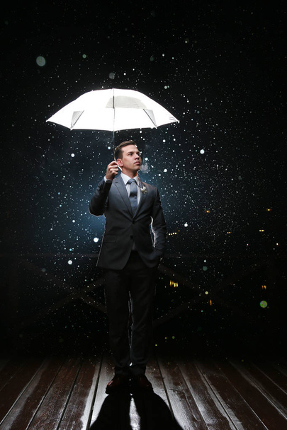 Man in classic suit with  white umbrella in flash lights and rain drops - Foto, afbeelding
