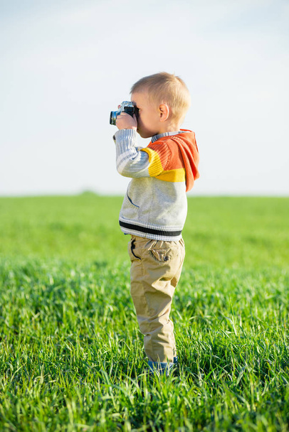 Little boy with an old camera shooting outdoor. - Photo, image