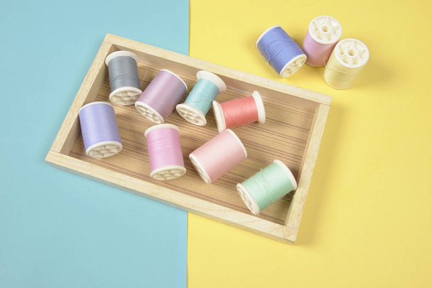 Flat lay of colored thread rolls for sewing on two tone backgrou - Фото, изображение